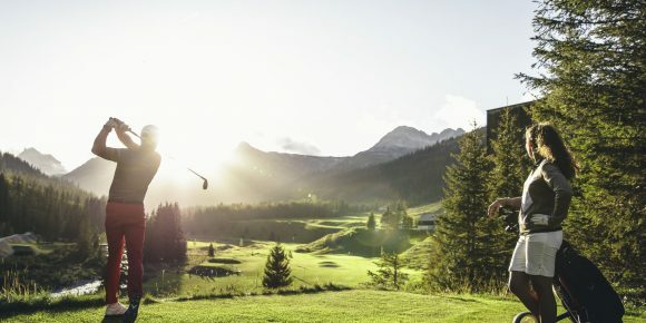 Couple teeing off on the sunny golf course in Lech. 